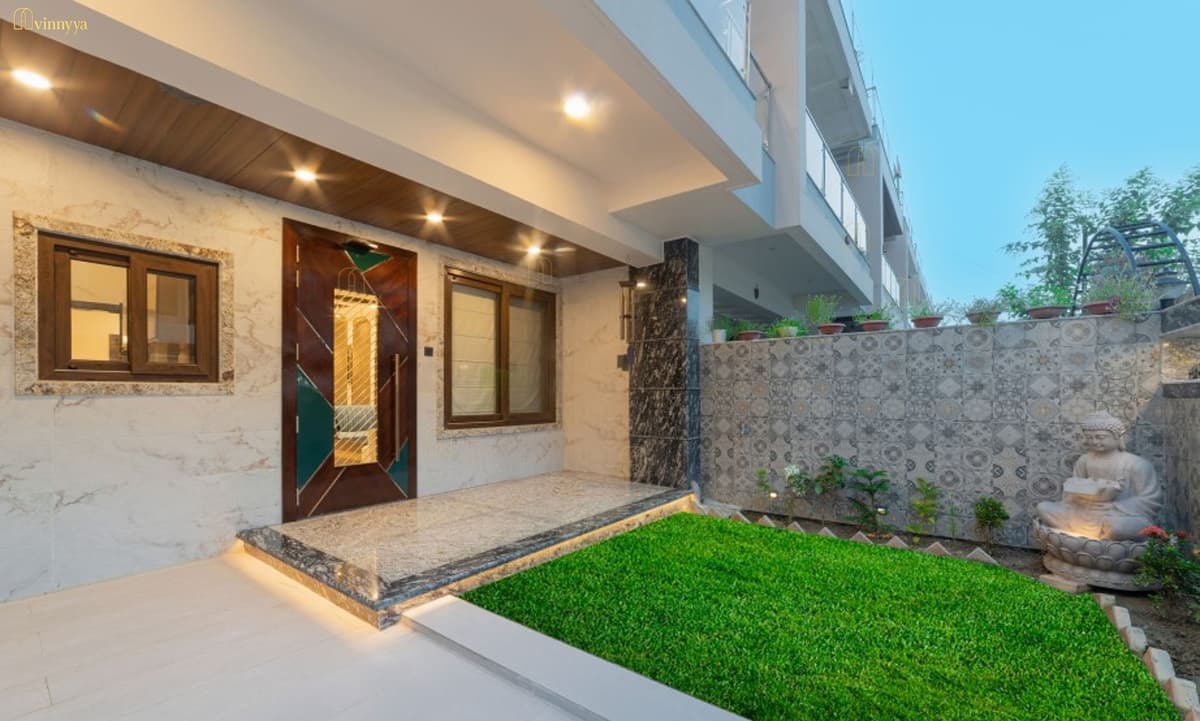 Villa entrance with a lit timber soffit and stone wall — Orabella, Varanasi